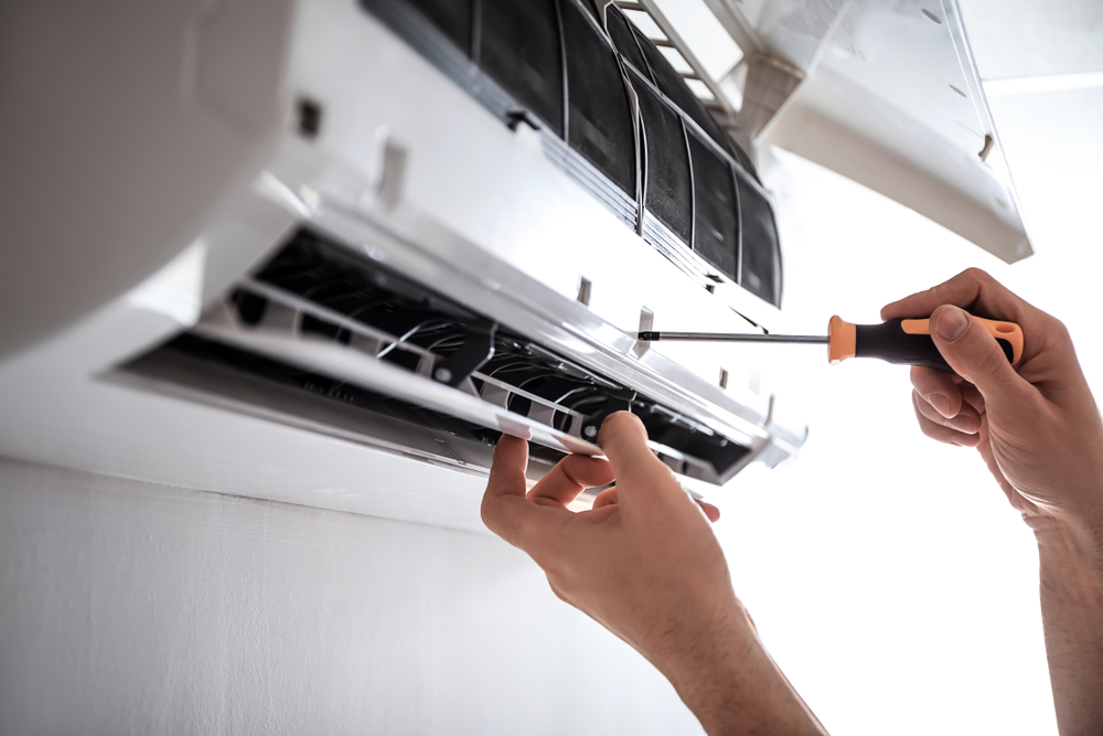 Technician repairing air conditioner indoors